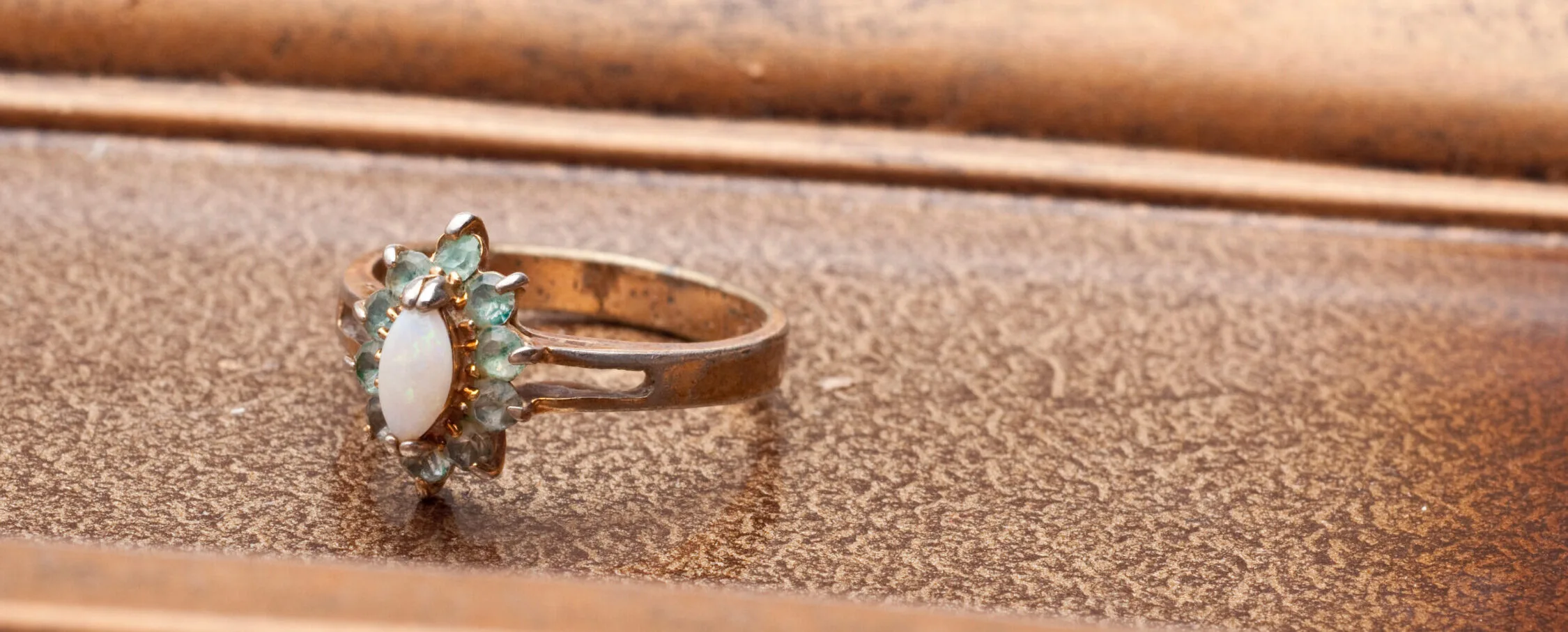Antique Victorian opal and peridot cluster ring on a wooden surface