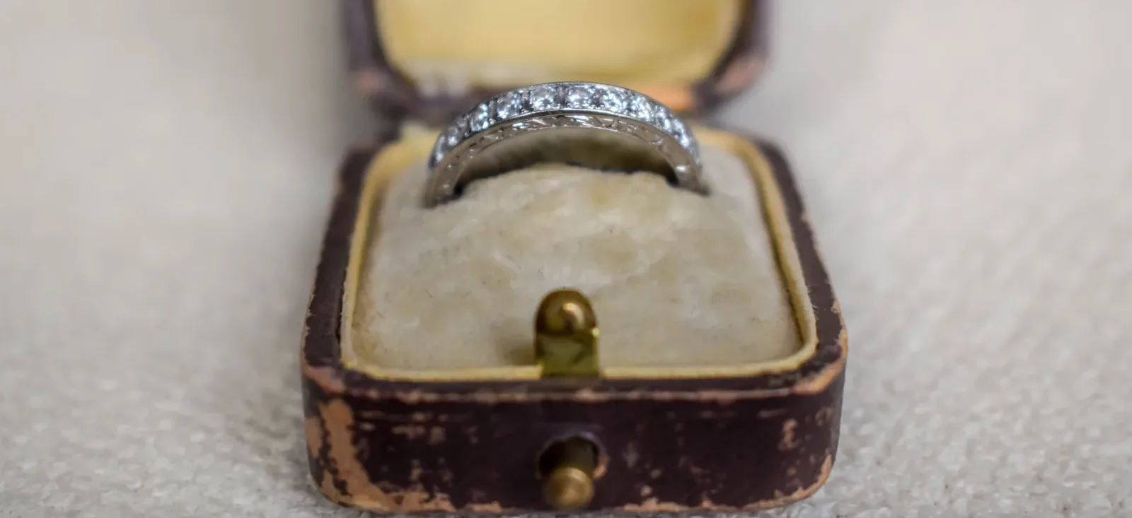 Antique platinum and diamond ring in an open 1920s leather ring case lined with cream velvet